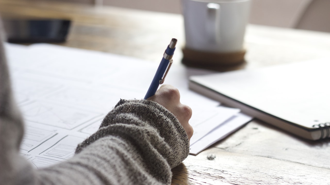 A study desk with an open notebook, pen, and coffee cup